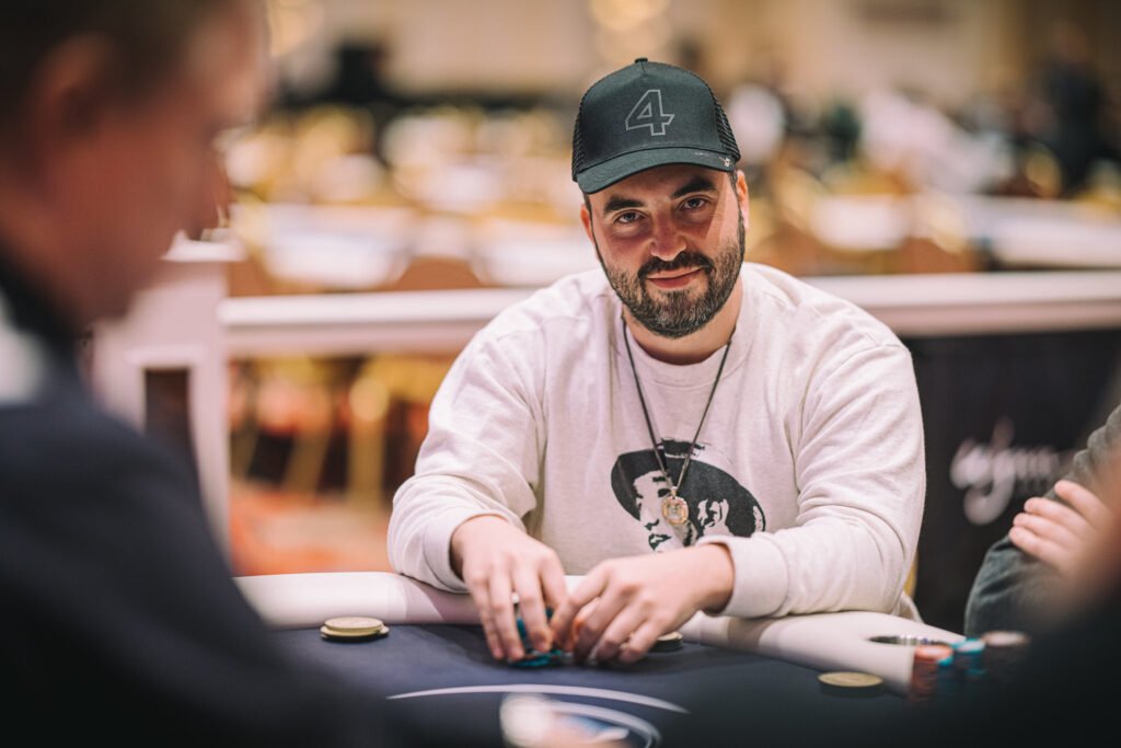 Man wearing cap and sunglasses playing poker at a table with chips